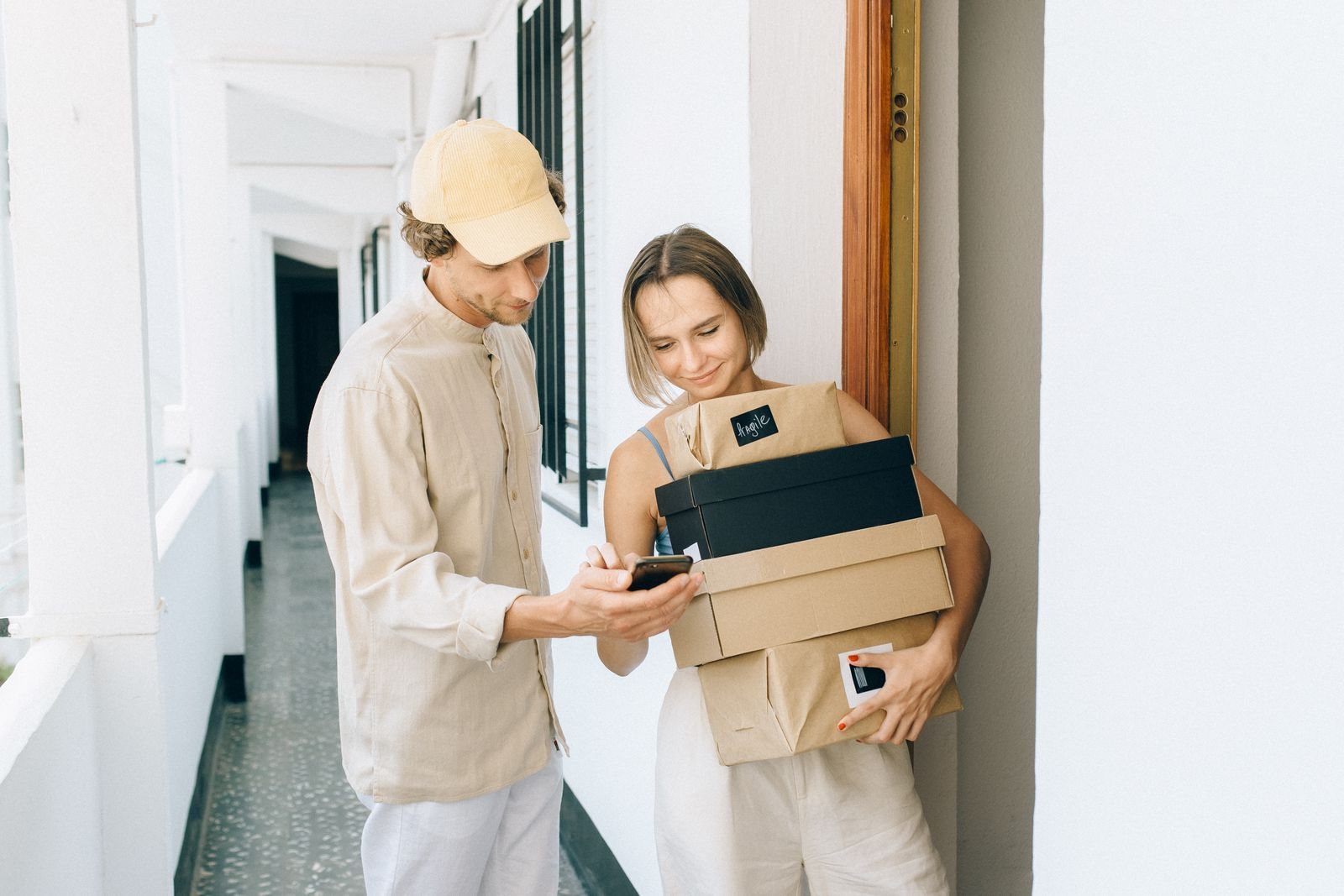 Un repartidor muestra en su teléfono la confirmación de entrega a una clienta que recibe sus cajas